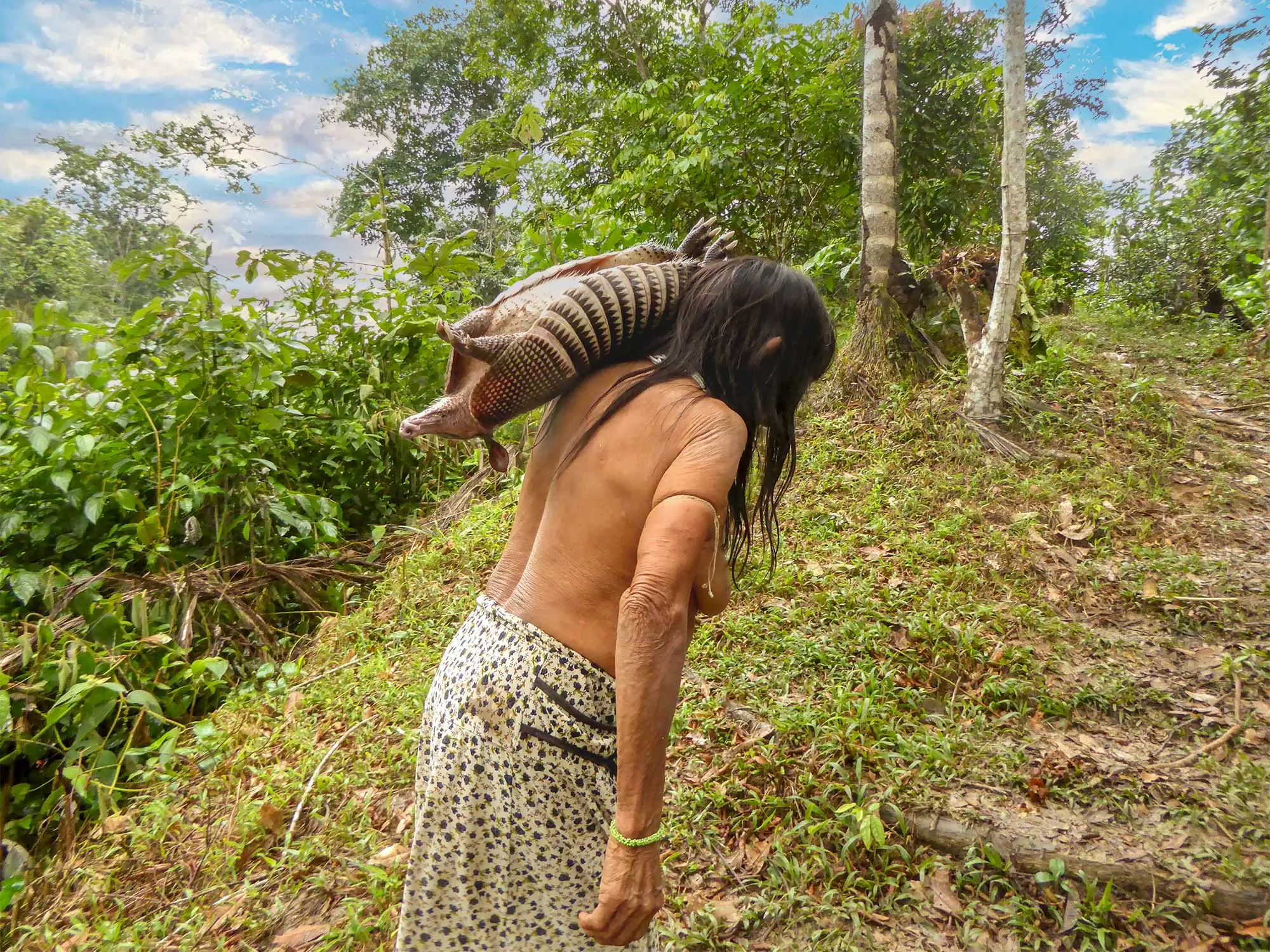 Matses elder woman carrying armadillo Amazon rainforest